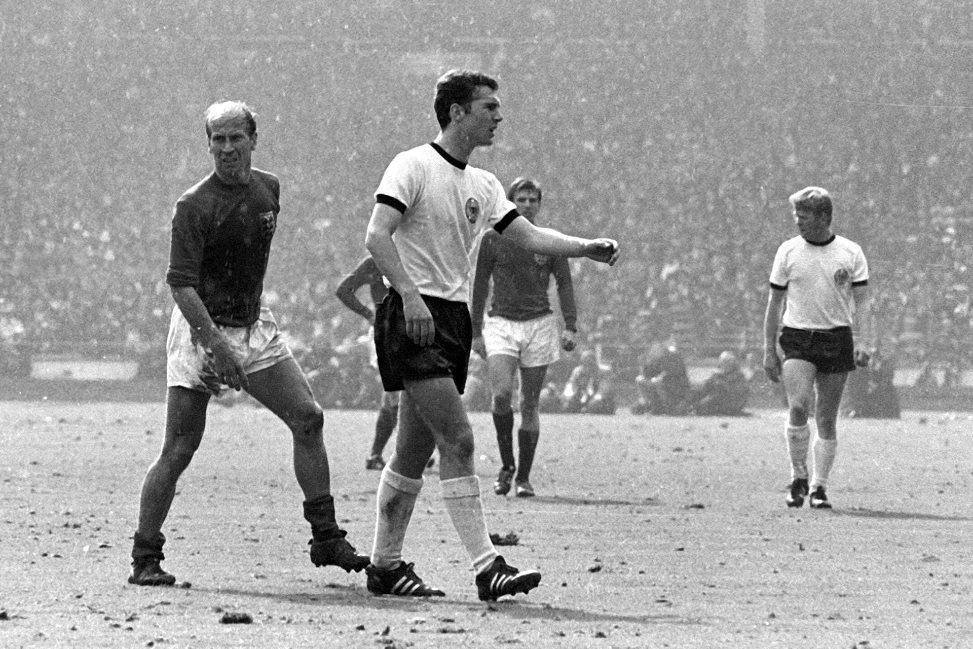 Bei der WM 1966 in England geht Beckenbauers Stern auf. Als defensiver Mittelfeldspieler erzielt er insgesamt vier Tore und belegt den dritten Platz in der Torschützenliste. Im Endspiel gegen England ist er der Sonderbewacher des damaligen Superstars Bobby Charlton (l.). Hinterher stellt sich heraus, dass Charlton wiederum den Auftrag hatte, Beckenbauer zu bewachen. Beide neutralisieren sich.