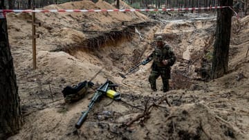 Ein Soldat untersucht eines der Gräber, die in einem Wald in Izyum gefunden wurden.