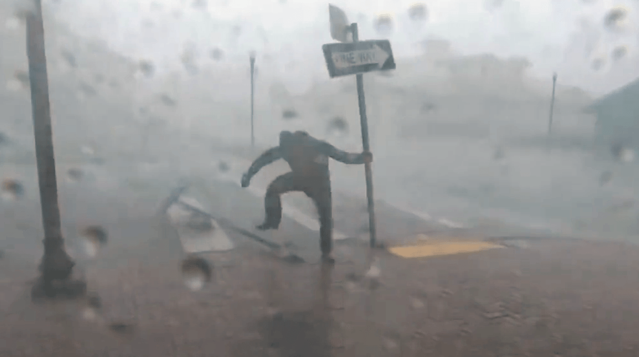 Der Wettermoderator klammert sich im Hurrikan an ein Straßenschild.