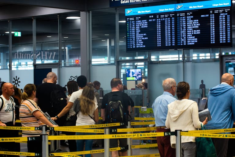 Reisende warten vor einem Check-In-Schalter am Kölner Flughafen (Archivbild): Die Warteschlangen sind Hunderte Meter lang.