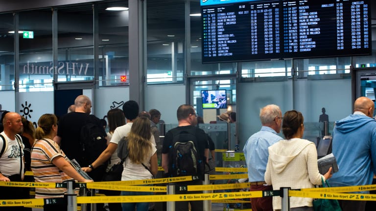 Reisende warten vor einem Check-In-Schalter am Kölner Flughafen (Archivbild): Die Warteschlangen sind Hunderte Meter lang.