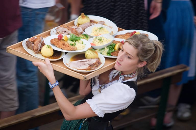 Kellnerin mit Essen auf der Wiesn (Symbolbild): Für Speis und Trank muss zuweilen tief in die Tasche gegriffen werden.