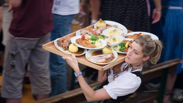 Kellnerin mit Essen auf der Wiesn (Symbolbild): Für Speis und Trank muss zuweilen tief in die Tasche gegriffen werden.