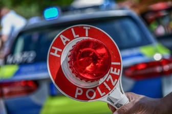 Eine Polizeikelle vor einem Einsatzfahrzeug (Symbolfoto): Den BMW-Fahrer erwarten mehrere Ermittlungsverfahren.