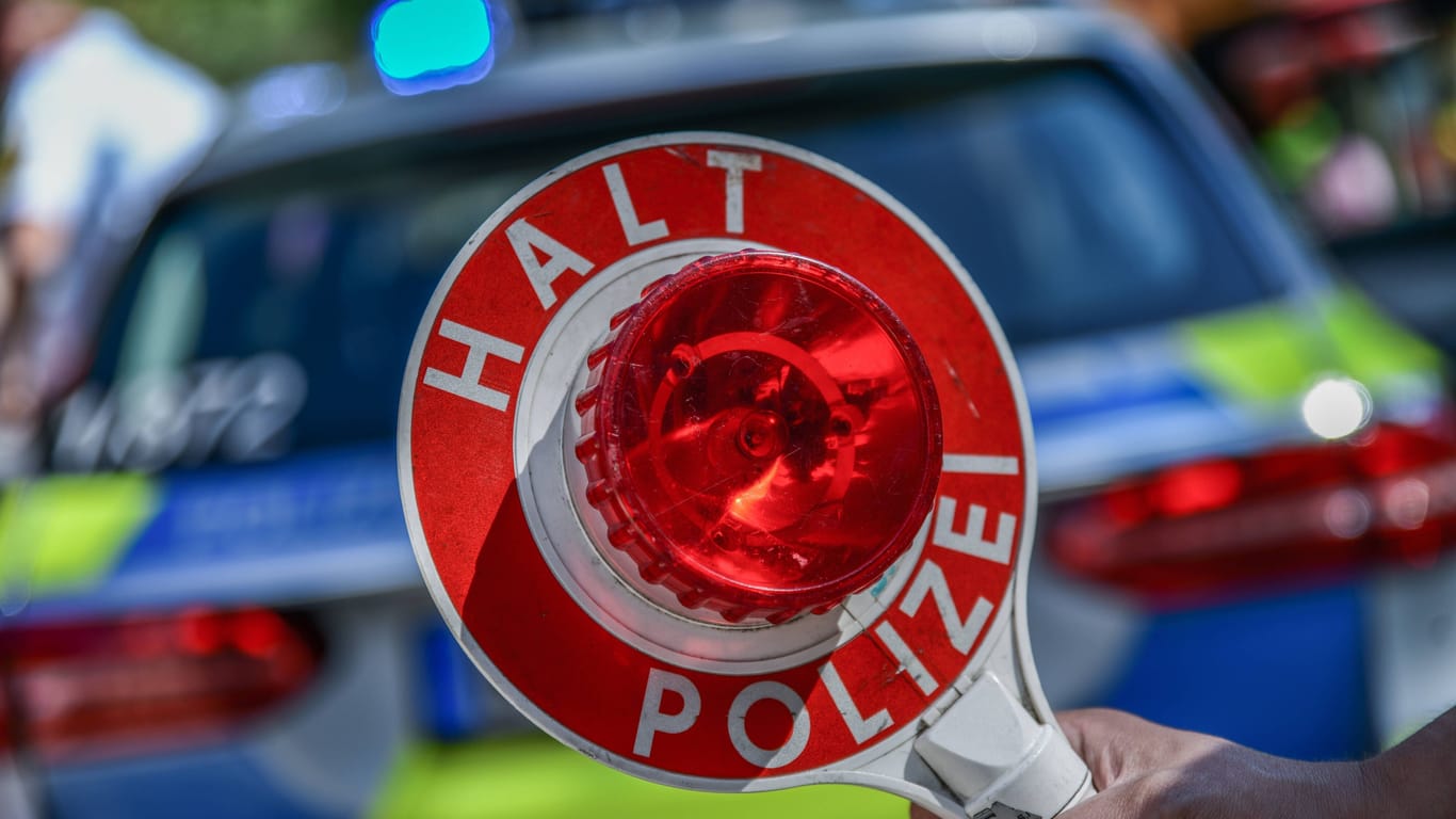 Eine Polizeikelle vor einem Einsatzfahrzeug (Symbolfoto): Den BMW-Fahrer erwarten mehrere Ermittlungsverfahren.