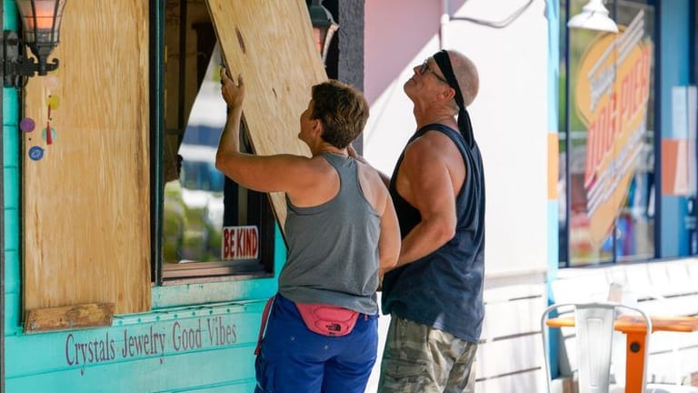 Lisa Bromfield und Mike Sernett bringen eine Sperrholzplatte an den Schaufenstern ihres Geschäfts im US-Bundesstaat Florida an, um sich auf die Ankunft von Hurrikan Ian vorzubereiten.
