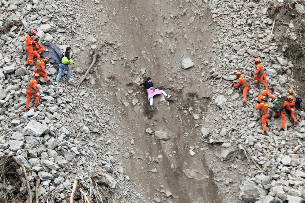 Ein Rettungsteam versucht eine Frau nahe der Stadt Moxi von einem Hang zu retten.