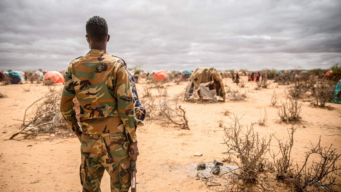 Ein Soldat beobachtet ein Hilfslager für geflüchtete Somalierinnen und Somalier in der Nähe von Dollow, Jubalans, Somalia. Eine Million Menschen sind bereits von der dürrebedingten Hungersnot betroffen.
