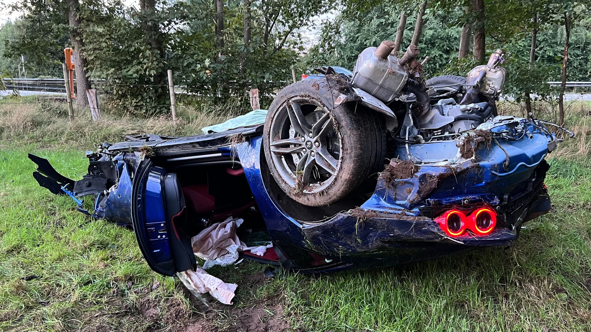 Der demolierte Ferrari liegt auf dem Dach neben der Autobahn: Beide Insassen wurden nur leicht verletzt.