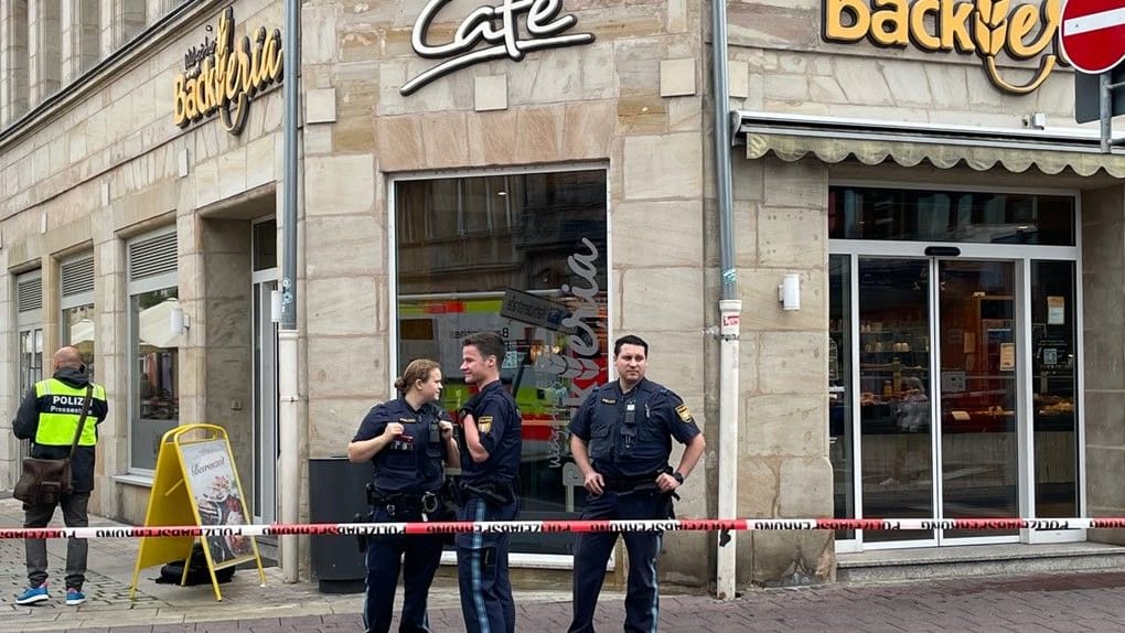 Polizeibeamte stehen hinter einer Absperrung vor einer Bäckerei: Dort kam es zu einem Messerangriff. Polizeibeamte stehen hinter einer Absperrung vor einer Bäckerei: Dort kam es zu einem Messerangriff.