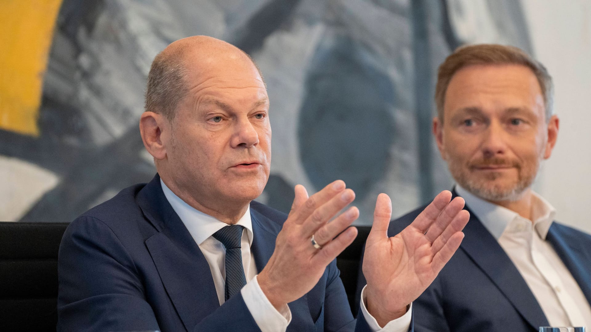 Olaf Scholz: Der Bundeskanzler neben Christian Lindner und vor einem auffälligen Wandgemälde.