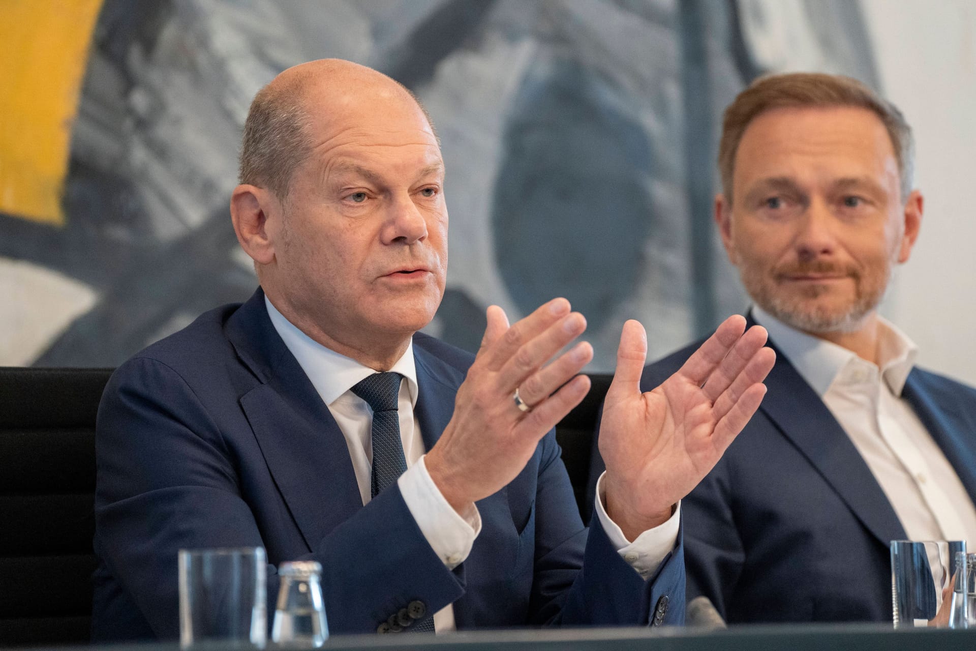 Olaf Scholz: Der Bundeskanzler neben Christian Lindner und vor einem auffälligen Wandgemälde.