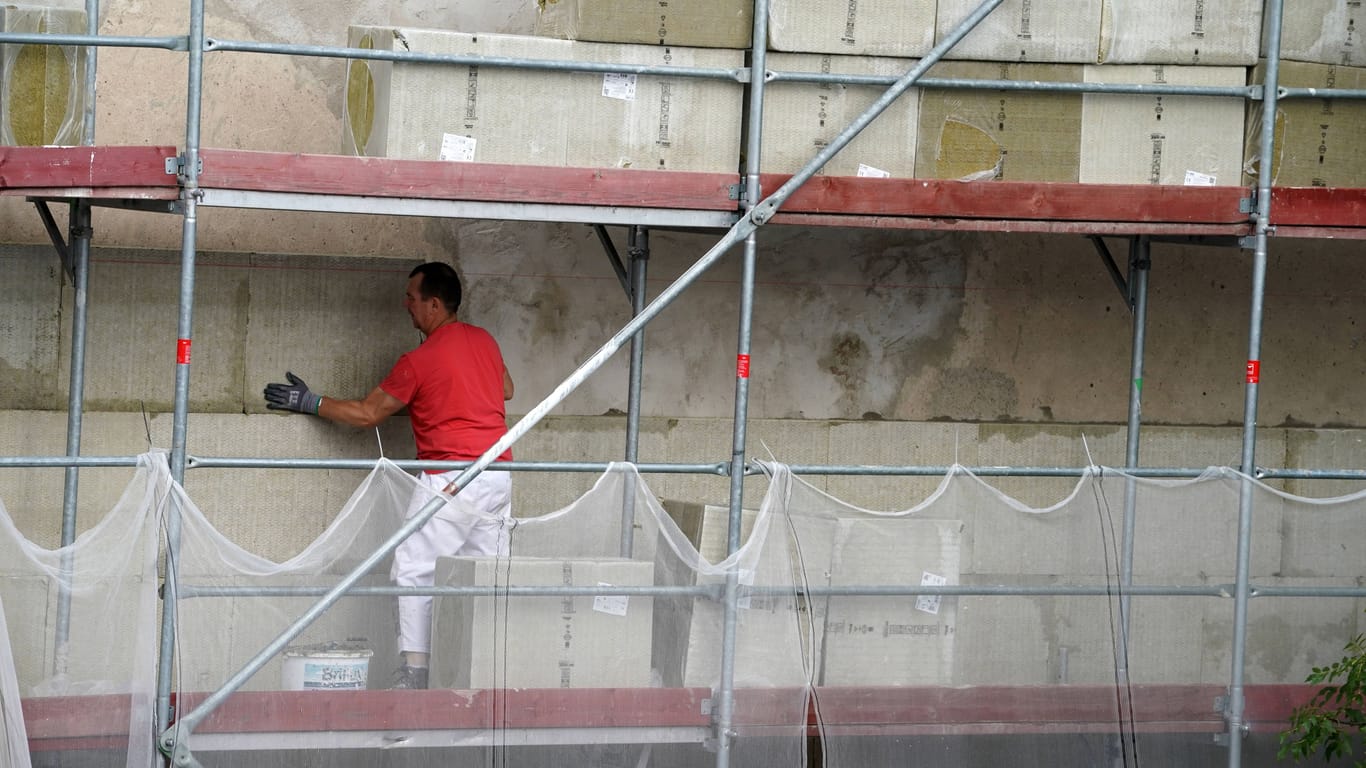 Bauarbeiter bei der Fassadendämmung (Symbolbild): Die Baubranche leidet unter hohen Energiekosten und Lieferschwierigkeiten.