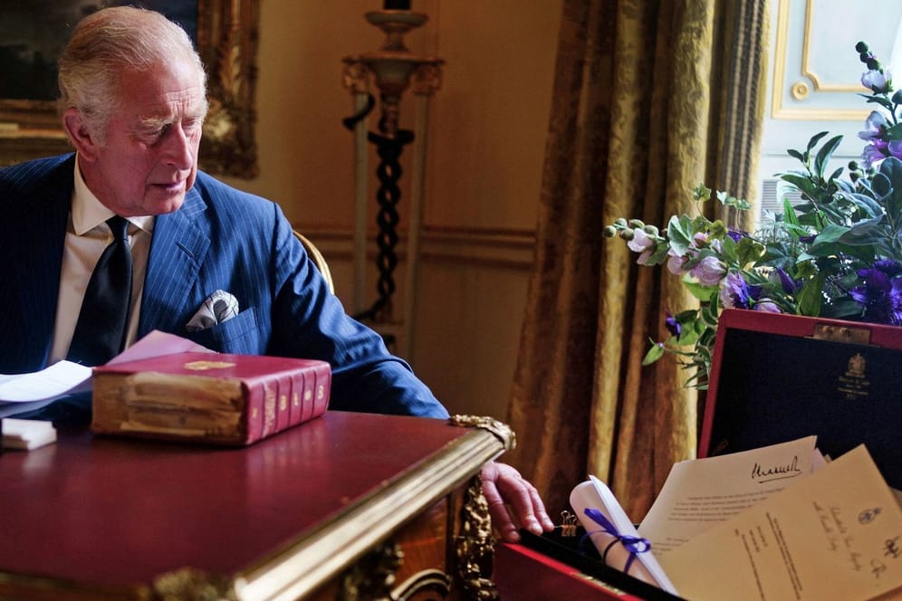König Charles III. an seinem Schreibtisch, links von ihm die Red Box mit wichtigen Unterlagen.