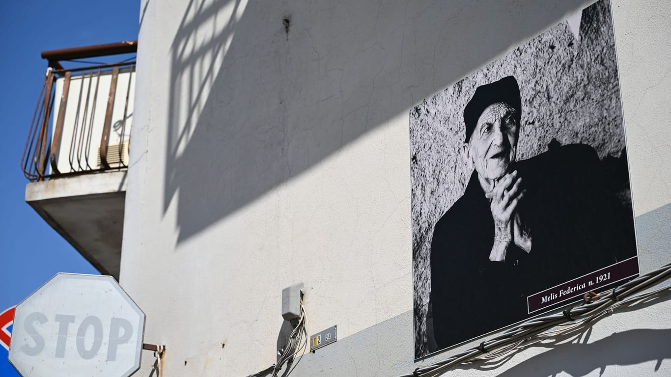 Dorf Perdasdefogu: An der Fassade der Häuser hängen Schwarz-Weiß-Fotos der Hundertjährigen aus dem Dorf mit deren Namen und Geburtsjahr.