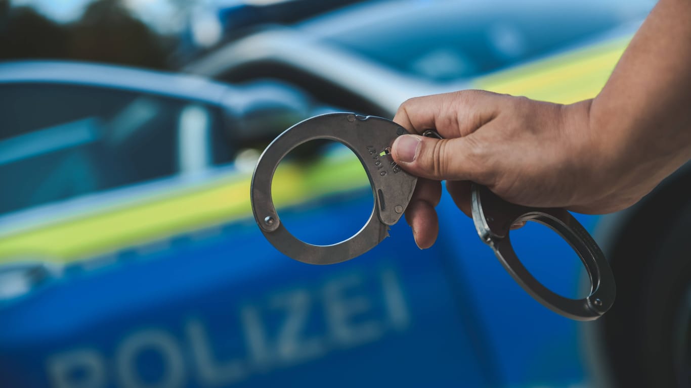 Ein Polizist mit Handschellen (Symbolbild): Nach Schüssen aus einem Auto hat sich ein Tatverdächtiger gestellt.