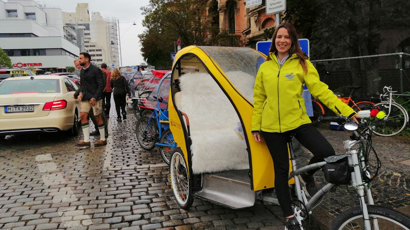 Rikscha-Fahrerin Sarah Brand auf der Straße am Oktoberfest-Gelände. Sie arbeitet gemeinsam mit ihrer Zwillingsschwester als Fahrrad-Taxi in diesem Jahr.