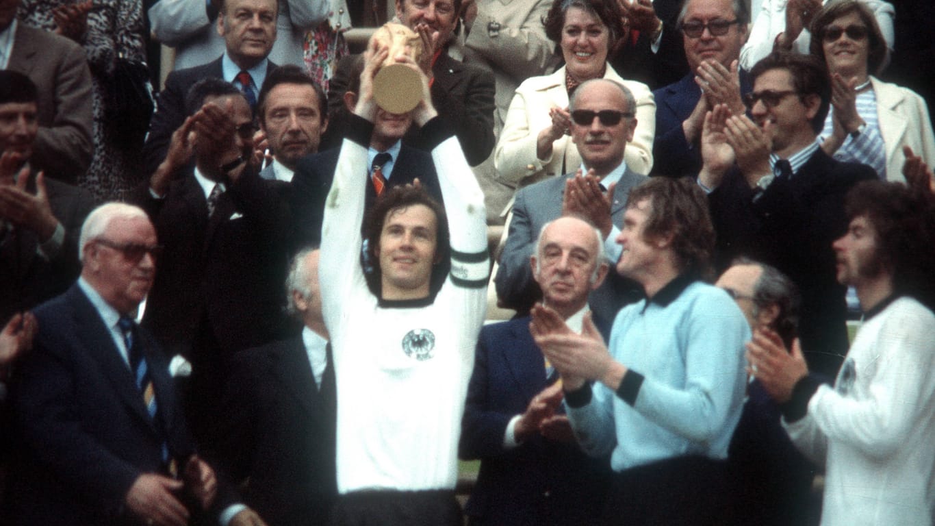 Franz Beckenbauer: Der Kaiser darf als Spieler 1974 den WM-Pokal in seinem "Wohnzimmer" im Münchner Olympiastadion hochhalten, unter anderem Paul Breitner und Sepp Maier (v.r.) gehören zur Nationalmannschaft.