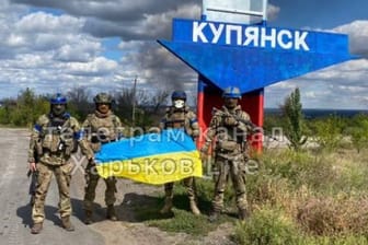 Ukrainische Soldaten vor dem Ortseingangsschild von Kupiansk: Der Ort ist das zentrale Drehkreuz für den russischen Nachschub in der Ostukraine.