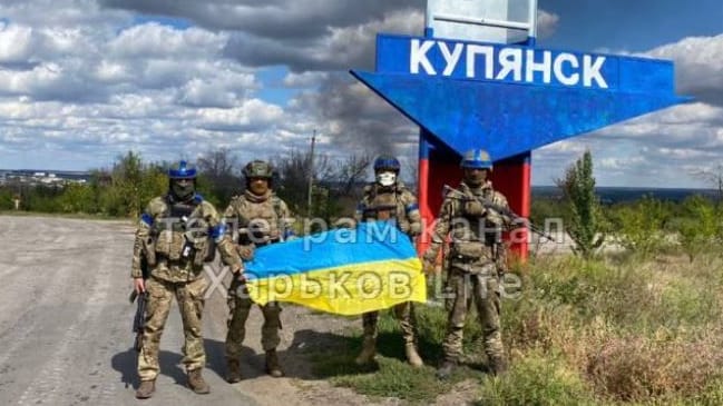 Ukrainische Soldaten vor dem Ortseingangsschild von Kupiansk: Der Ort ist das zentrale Drehkreuz für den russischen Nachschub in der Ostukraine.