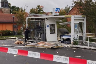 Polizisten sichern Spuren an einem gesprengten Geldautomaten: Die Trümmer waren auf dem Parkplatz des anliegenden Discounters verteilt.