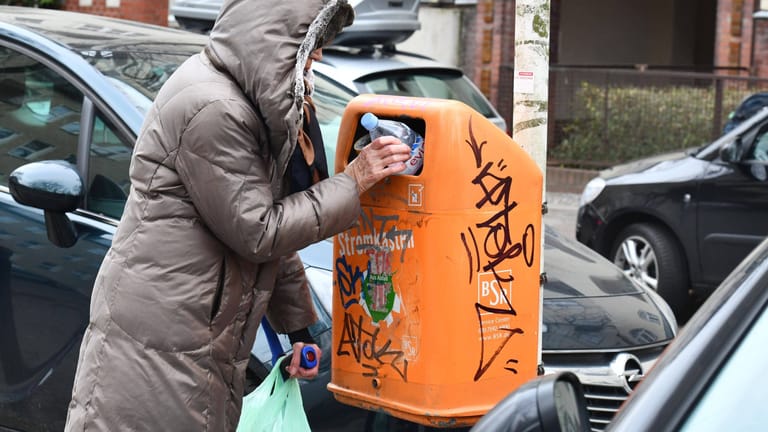 Eine ältere Frau fischt eine Pfandflasche aus dem Mülleimer. Immer mehr Rentner stocken damit finanziell auf.