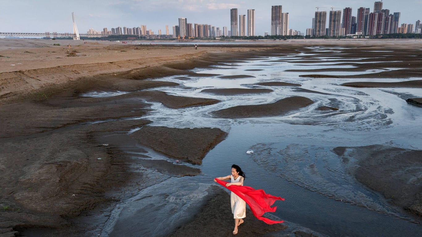 Eine Cinesin steht im ausgetrockneten Flussbett des Jangtse bei Wuhan: In Pakistan und vielen anderen Erdregionen hat das Jahr 2022 bereits zahlreiche Extremwetterereignisse gebracht.