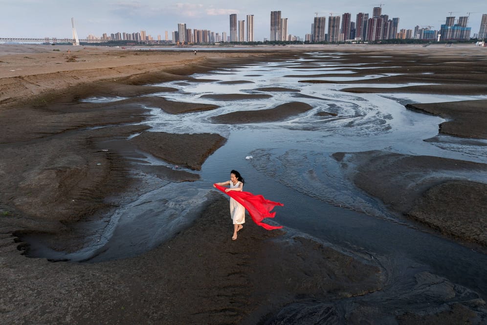 Eine Cinesin steht im ausgetrockneten Flussbett des Jangtse bei Wuhan: In Pakistan und vielen anderen Erdregionen hat das Jahr 2022 bereits zahlreiche Extremwetterereignisse gebracht.