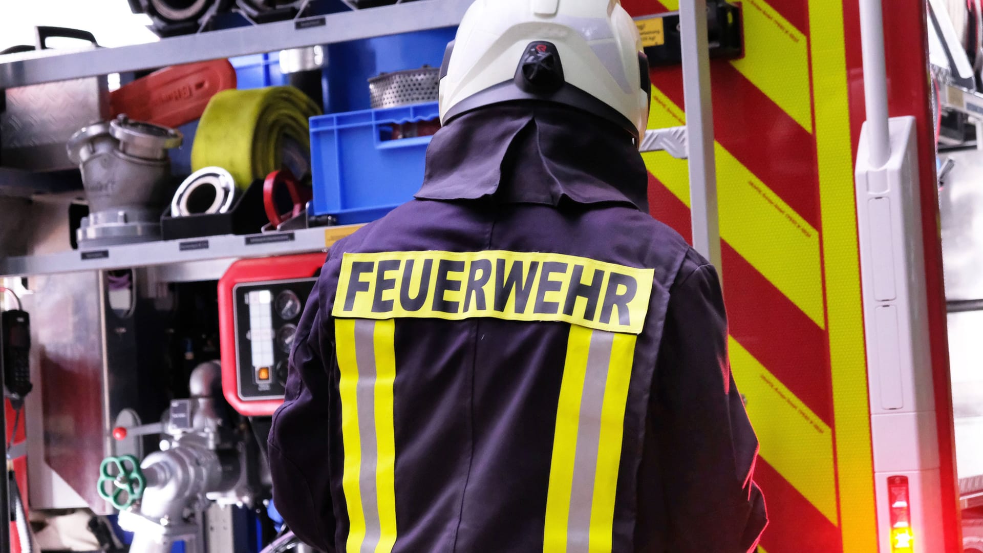 Ein Mitarbeiter der Feuerwehr steht vor einem Löschfahrzeug (Archivbild): Mehr als 20 Hausbewohner konnten sich ins Freie retten.