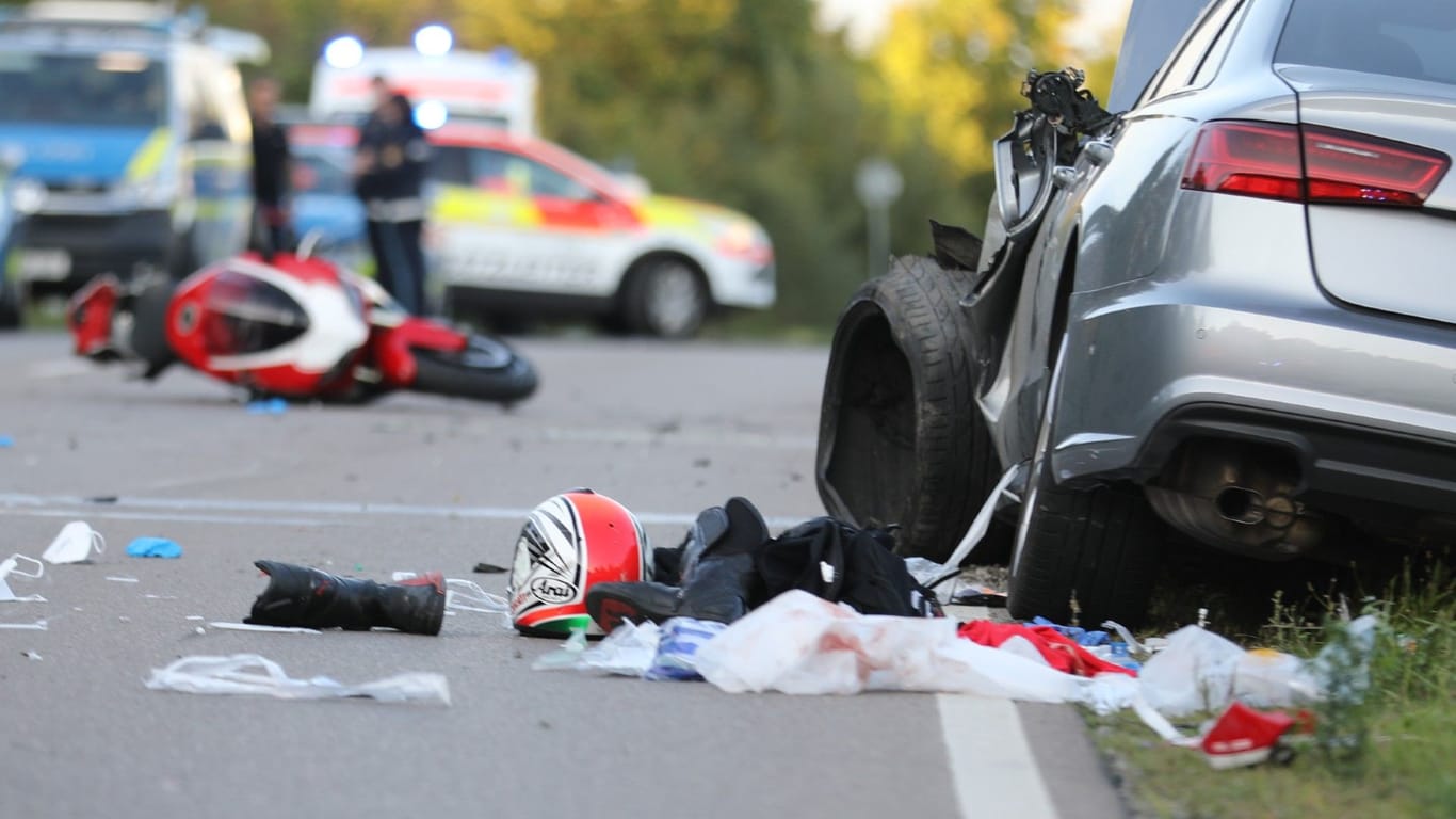 Die Unfallstelle: Die Front des Audis ist schwer beschädigt, auf der Straße liegen Sachen des Motorradfahrers.