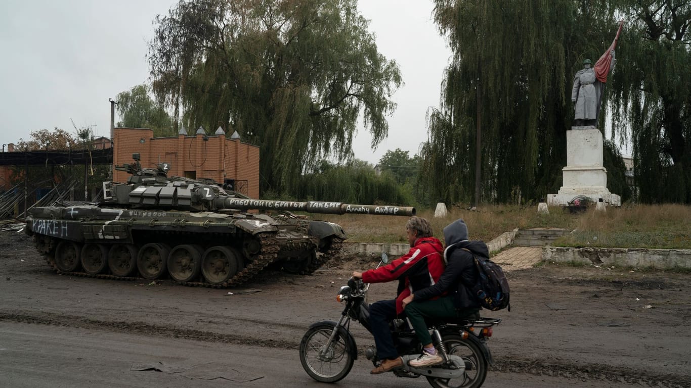 Ein Motorrad fährt an einem zerstörten russischen Panzer vorbei: Durch die ukrainische Gegenoffensive ist die russische Front in der Region Charkiw zusammengebrochen.