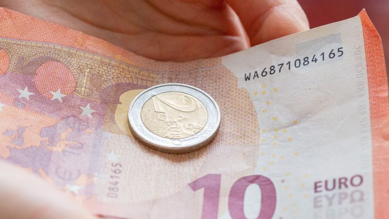Person hält 12 Euro in der Hand: Besonders in Mecklenburg-Vorpommern profitieren Arbeitnehmerinnen und Arbeitnehmer vom neuen Mindestlohn.