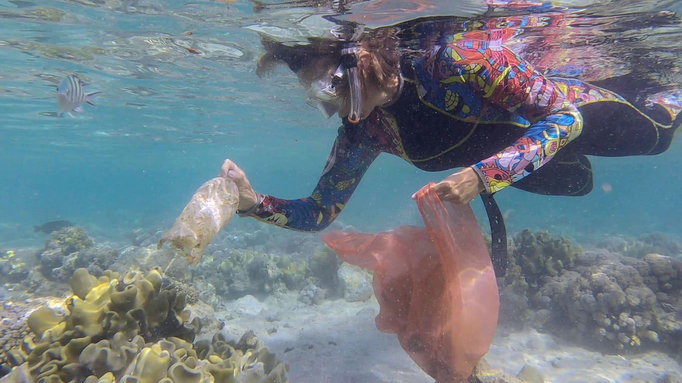Frau in Tauchausrüstung sammelt Plastikmüll: Die Weltmeere füllen sich unaufhaltsam mit Plastikmüll.