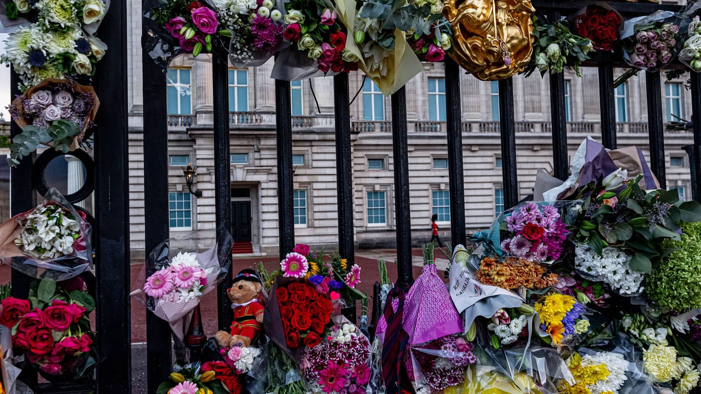 Menschen legen Blumen vor dem Buckingham-Palast nieder.
