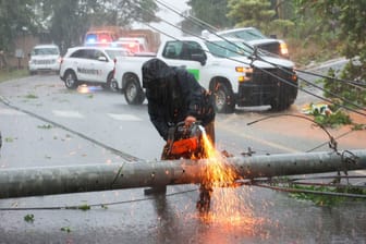 Puerto Rico, Cayey: Ein Arbeiter zerschneidet einen Strommasten, der durch den Hurrikan Fiona umgestürzt ist und eine Straße blockiert.