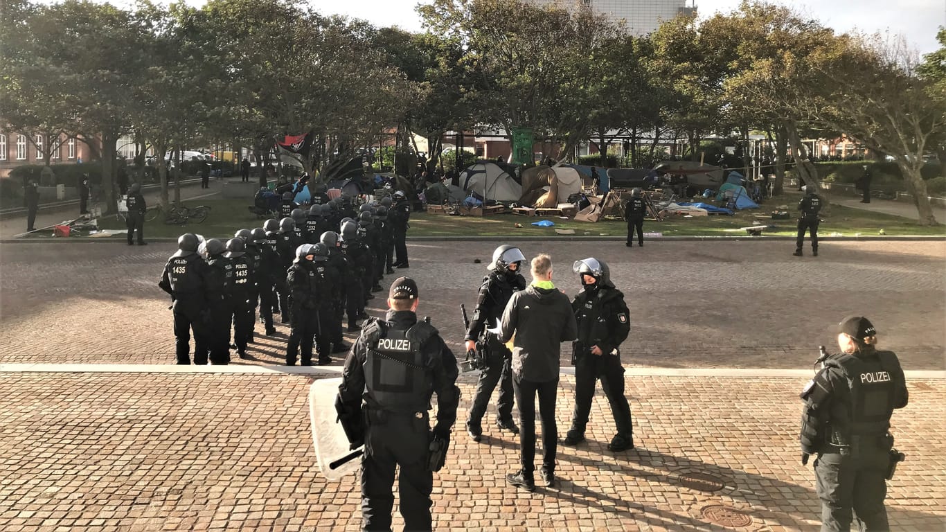 Die Lage am Rathauspark in Westerland: Vorne in der Mitte ist Bürgermeister Nikolas Häckel zu sehen, der mit Polizisten darauf wartet, dass die Punks ihr Camp verlassen.