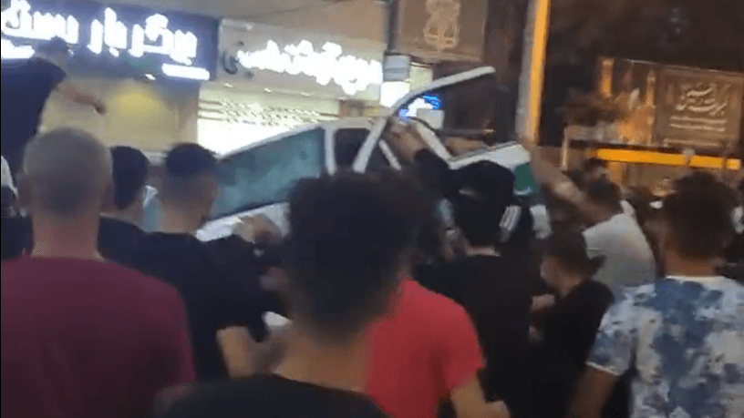 Demonstran menaruh mobil polisi di kepala mereka