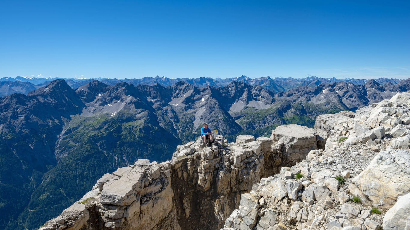 Ein Wanderer sitzt auf einem Felsen am Gipfel des Hochvogel (Archivbild): Den Berg durchzieht ein riesiger Spalt.