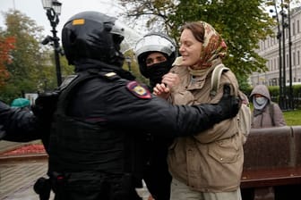 Bei einem Protest gegen die Teilmobilisierung in Moskau halten Polizisten eine Frau fest: Sogar mit Warnschüssen wird offenbar gegen die Demonstranten vorgegangen.