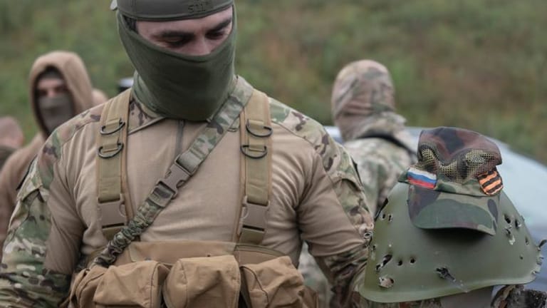 Ein ukrainischer Soldat hält den Helm eines russischen Soldaten in Händen (Archivbild): In dem Krieg kämpfen auch viele Ausländer, darunter einige wenige Deutsche.