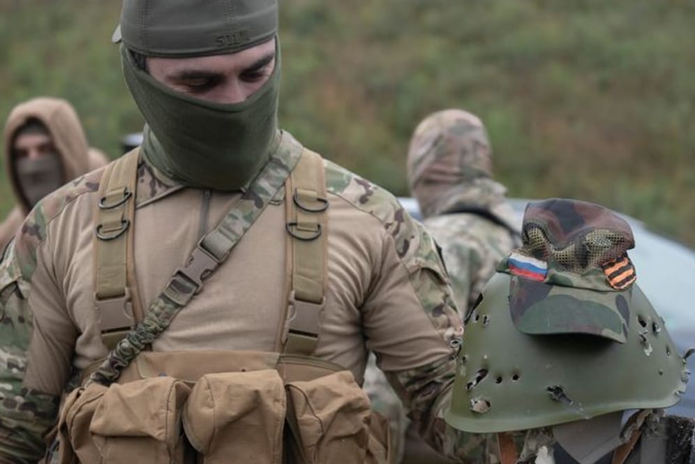 Ein ukrainischer Soldat hält den Helm eines russischen Soldaten in Händen (Archivbild): In dem Krieg kämpfen auch viele Ausländer, darunter einige wenige Deutsche.