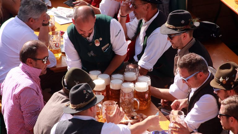 Eine Bedienung schleppt mehrere Maß Bier zu den Gästen auf dem Oktoberfest (Archivbild): Wer auf der Wiesn feiert, sollte mit Trinkgeld nicht geizen.