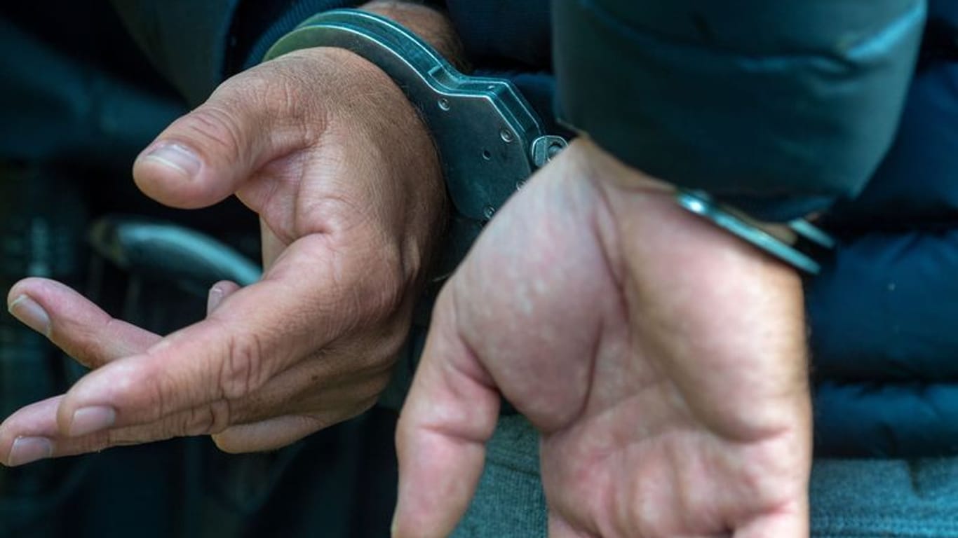 Ein Mann trägt Handschellen (Symbolfoto): Die Polizei hat einen Husumer festgenommen, der seine Frau getötet haben soll.