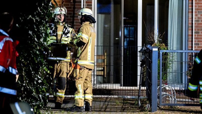 Einsatzkräfte der Feuerwehr stehen vor dem in Brand geratenen Altenheim in Wardenburg.