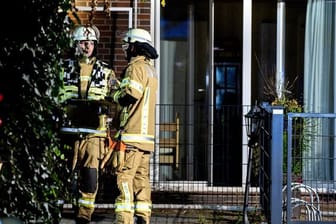 Einsatzkräfte der Feuerwehr stehen vor dem in Brand geratenen Altenheim in Wardenburg.