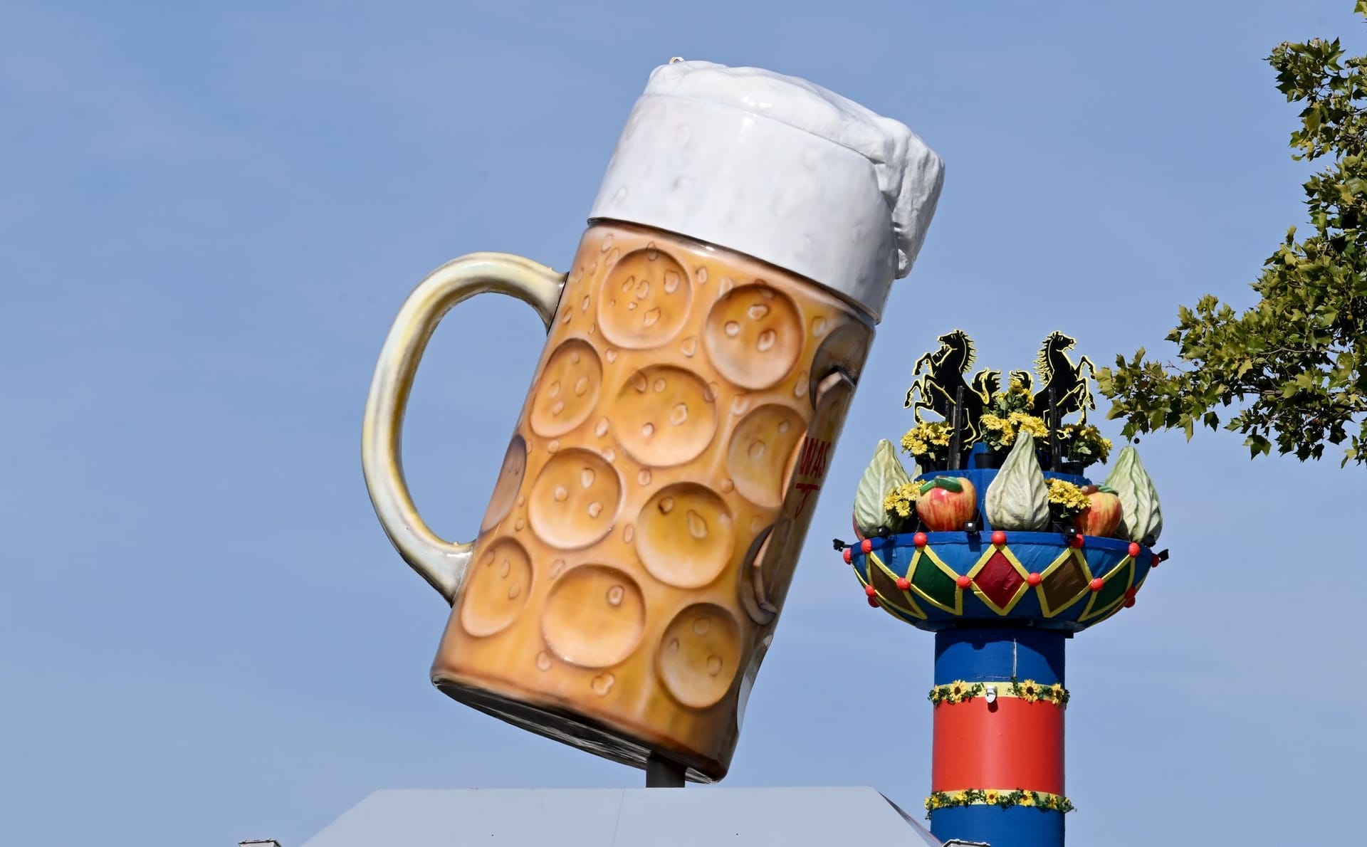 Ein riesiger Bierkrug steht am Eingang auf dem Festgelände Cannstatter Wasen, im Hintergrund ist die Fruchtsäule zu sehen. Ein riesiger Bierkrug steht am Eingang auf dem Festgelände Cannstatter Wasen, im Hintergrund ist die Fruchtsäule zu sehen.