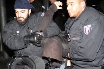 Polizisten führen einen Teilnehmer eines linken Gegenprotests ab: Er war offenbar Teil einer Straßenblockade.