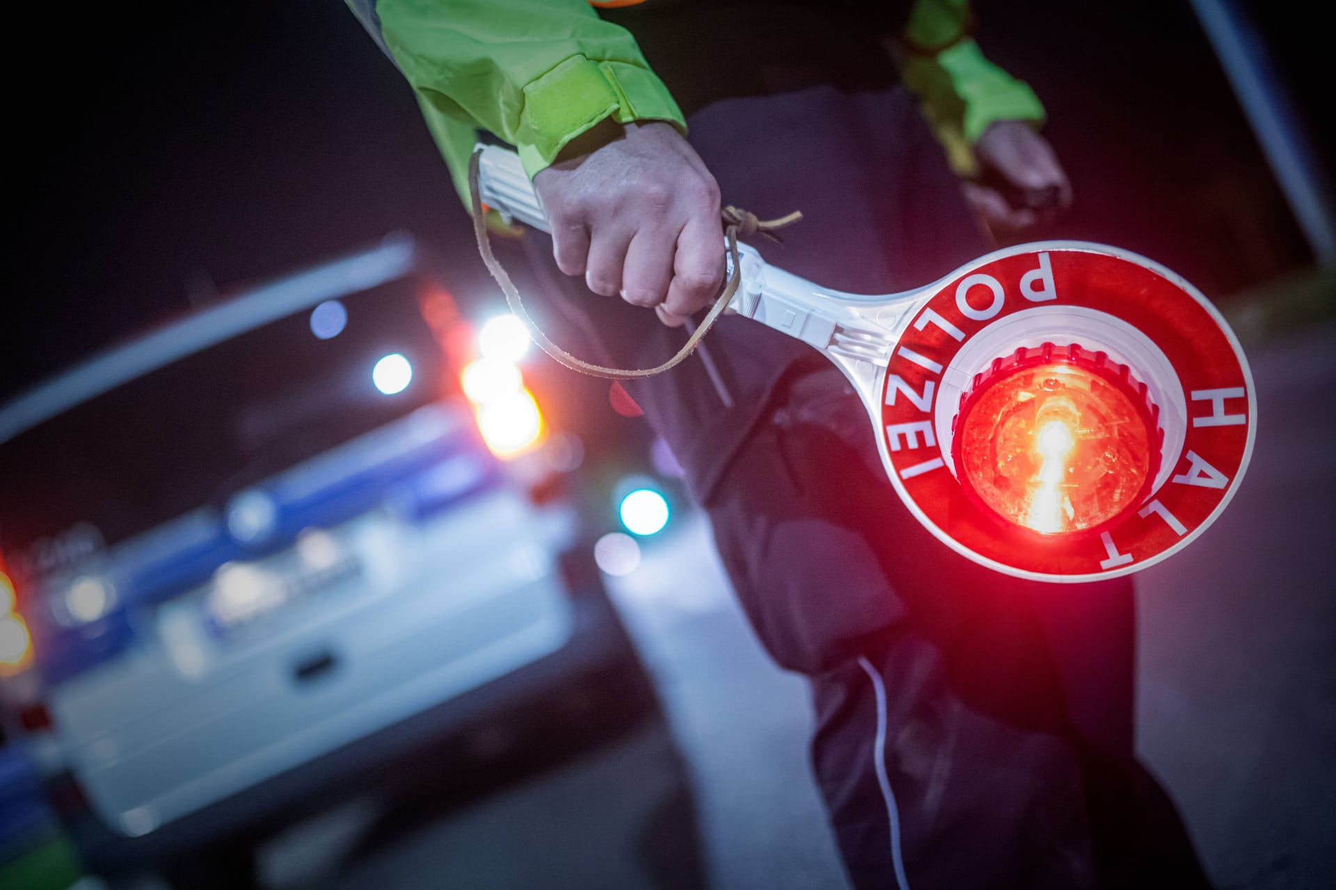 Ein Polizist hält ein "Stopp"-Zeichen in der Hand (Symbolbild): Der Fahrer wollte sich einer Kontrolle entziehen.