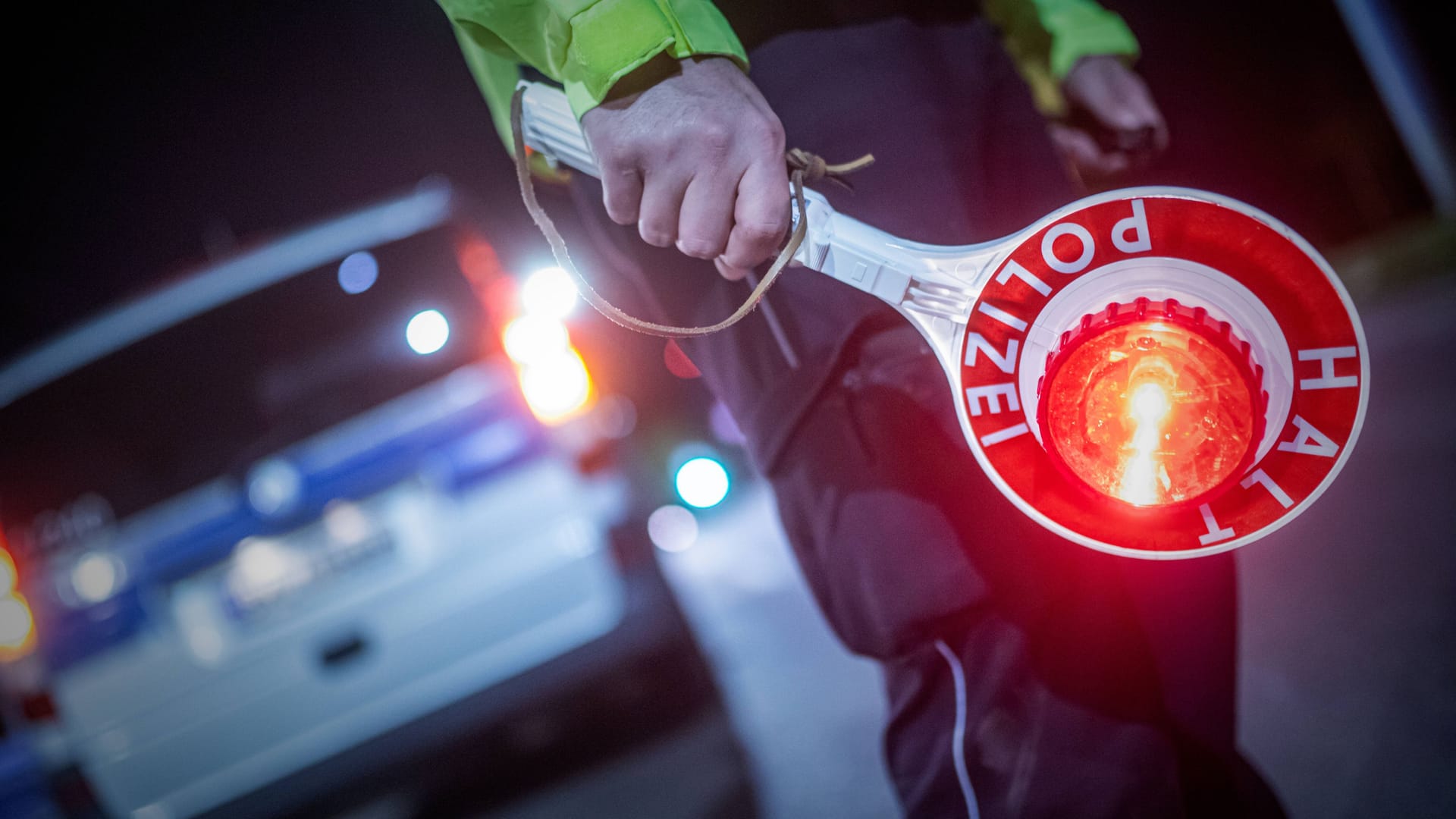 Ein Polizist hält ein "Stopp"-Zeichen in der Hand (Symbolbild): Der Fahrer wollte sich einer Kontrolle entziehen.