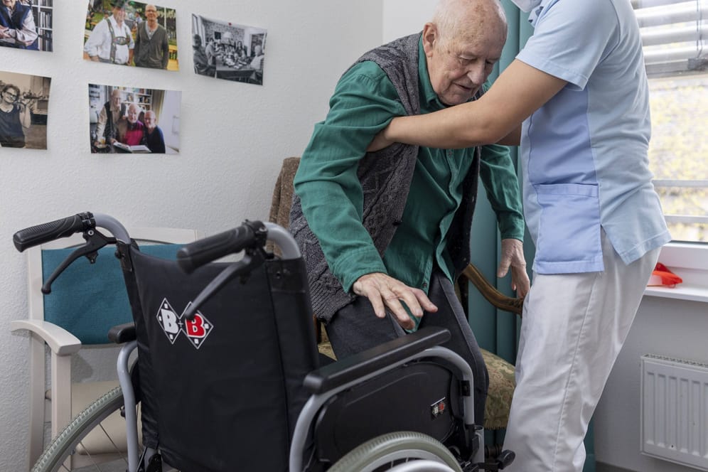 Ein Pfleger hilft einem älteren Mann aus dem Rollstuhl: Die Pflege wird absehbar ein großes Problem.